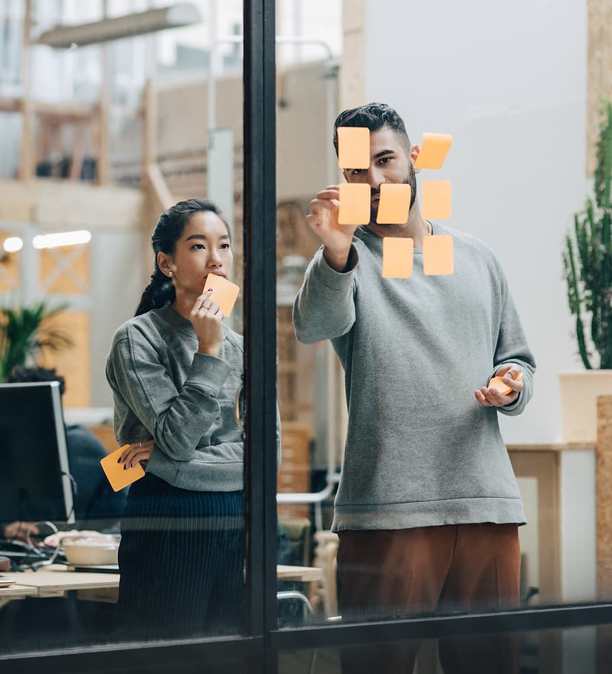 Colleagues planning with sticky notes on a glass wall